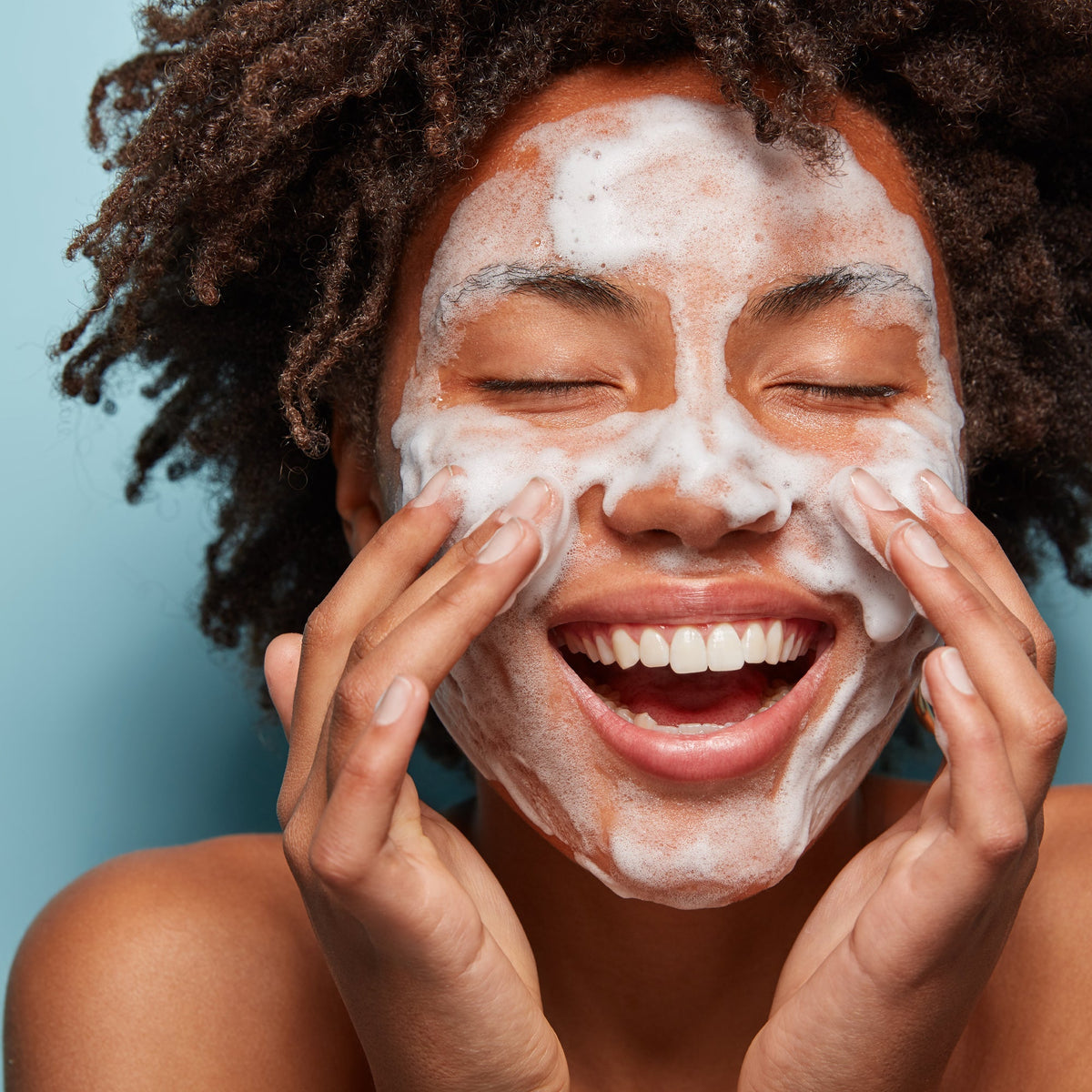 Donna sorridente che si deterge il viso con la schiuma