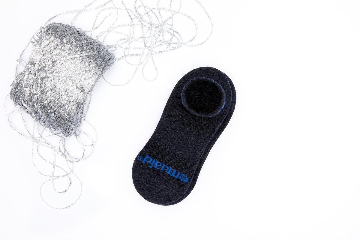 Schwarze Socke mit blauem Logo neben einem silbernen Faden auf weißem Hintergrund