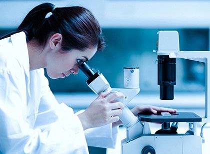 A picture of a woman looking into a microscope